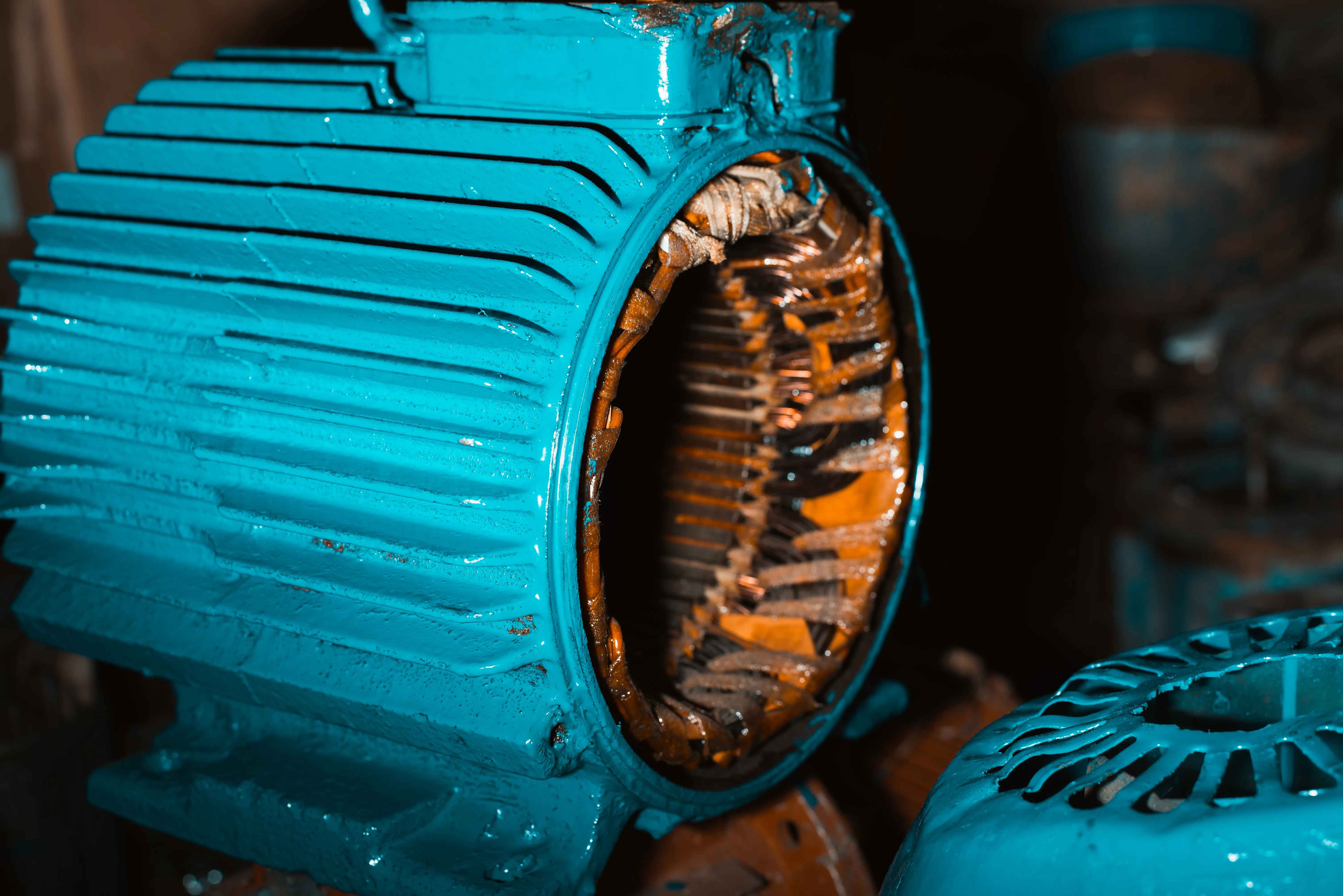 Reparación de diferentes tipos de embobinados de motor. Carcasa azul de un motor eléctrico mostrando uno de los tipos de embobinados de cobre deteriorados en su interior.